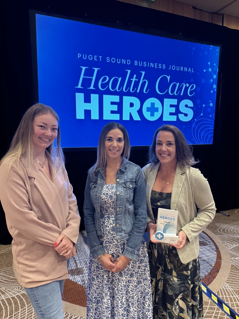 A group of women standing in front of a large screen holding an award.